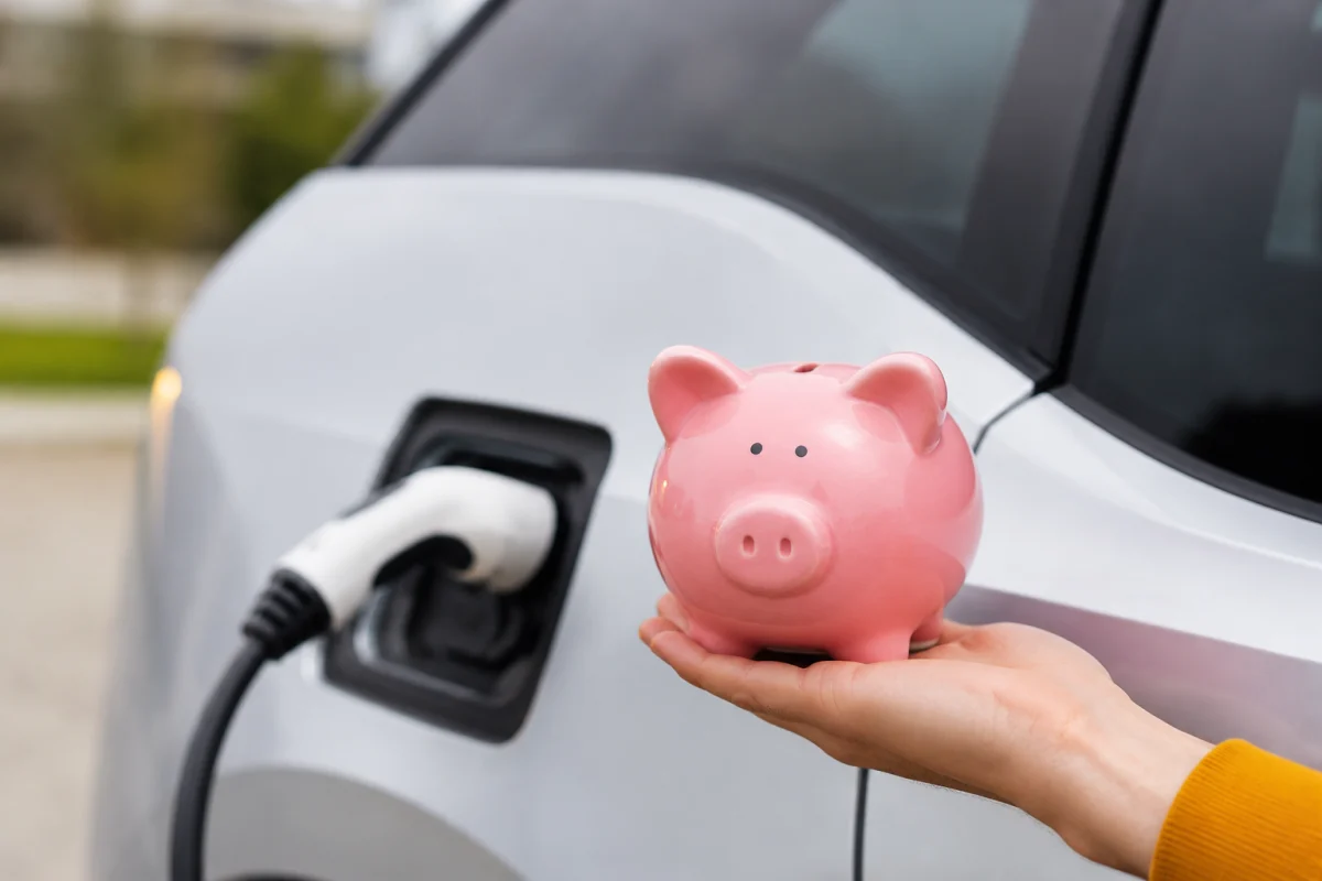 Toutes les aides pour acheter une voiture électrique et réduire son reste à payer Main branchant un câble de recharge sur la prise d'une voiture électrique blanche